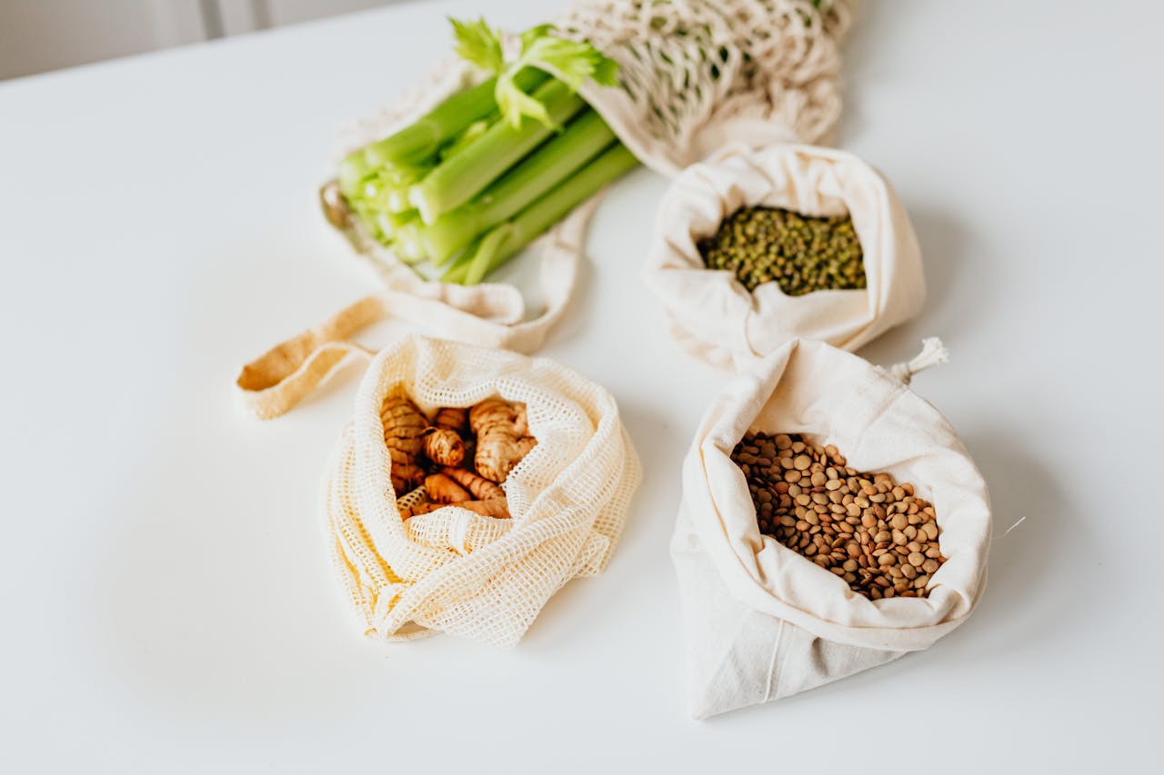 Reusable bags with fresh vegetables and lentils, promoting sustainable living.